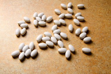 D vitamini hapları bir kum tezgahının üzerinde kaotik bir şekilde yatar.