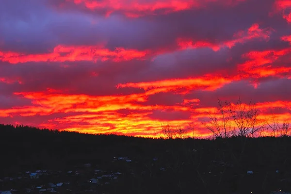 Coucher de soleil rouge-bleu sur la ville avec des nuages sombres. Silhouette sombre de la ville avec une belle aube . — Photo