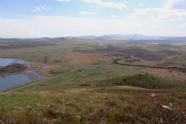 Gözlem güvertesinden, dağdan aşağıdaki güzel manzaraya bakın. Çiftlik, yol, orman, tepe, göl ve gökyüzünün manzarası.