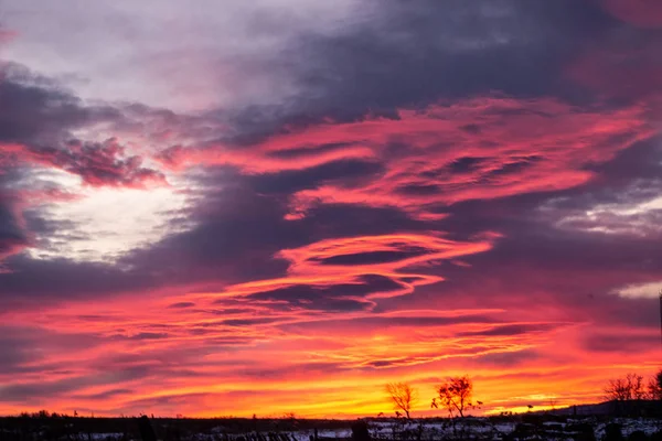 Красно-синий закат с темными облаками на окраине деревни. Темный зимний сельский силуэт с прекрасным восходом солнца. Художественно расплывчатый — стоковое фото