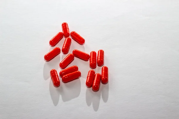 Pillole rosse sparse su un tavolo bianco. Layout per offerte speciali, pubblicità, sfondo web. Il concetto di medicina, farmacia e sanità. Spazio vuoto per testo o logo . — Foto Stock