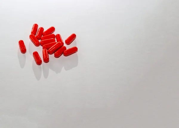 Spridda röda piller på vitt papper. Layout för specialerbjudanden, reklam, webb bakgrund. Begreppet medicin, apotek, sjukvård. Tomma utrymme för text, logotyp. Närbild, isolat av droger — Stockfoto