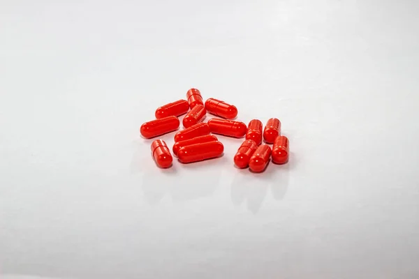 Roztroušené červené pilulky na bílém papíru. Rozvržení pro speciální nabídky, reklamy, webové zázemí. Koncept medicíny, farmacie, zdravotní péče. Prázdné místo pro text, logo. Detailní záběr, izolát drog — Stock fotografie