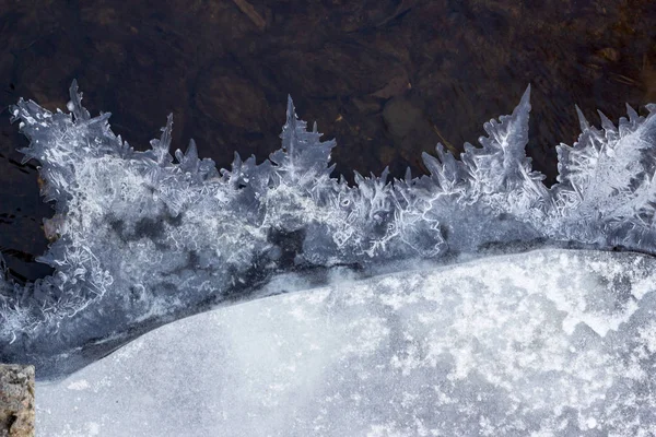IJs op de rivier in de winter. Schilderachtige vorst, kristallen op rivierijs over donker stromend water met een transparante bodem. Een close-up. Selectieve, zachte focus. — Stockfoto