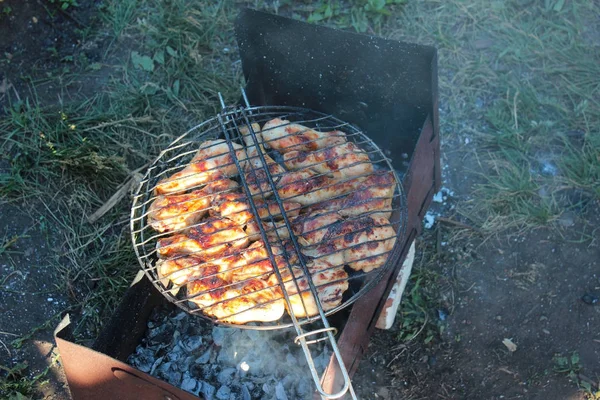Fűszeres pácolt csirkeláb sült egy nyári barbecue. Csirkelábak sült egy forró lángoló faszén grill, közelkép tetejére — Stock Fotó
