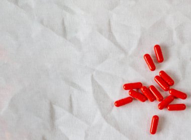Yellow pills on a white cloth. Photo background with capsules on a fabric texture. Copy space, place for text, advertisement