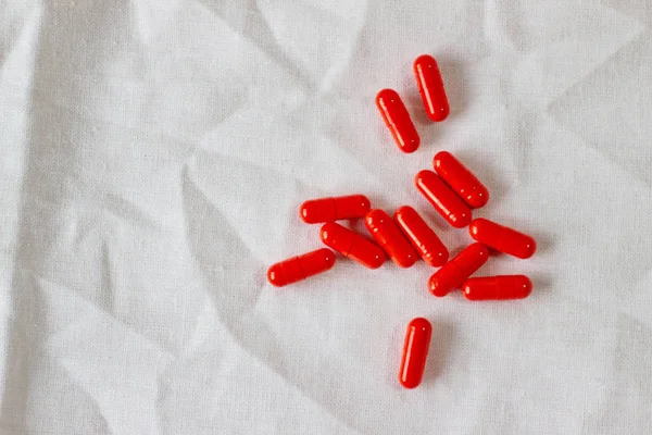 Red pills on a white cloth. Photo background with capsules on a fabric texture. Copy space, place for text. — 图库照片