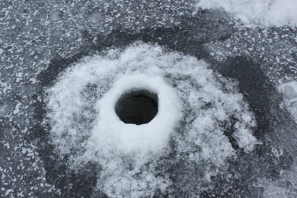 Winter fishing on the ice of a frozen lake. Ice hole in the river. Winter ice fishing, hobby, outdoor activities, lifestyle.