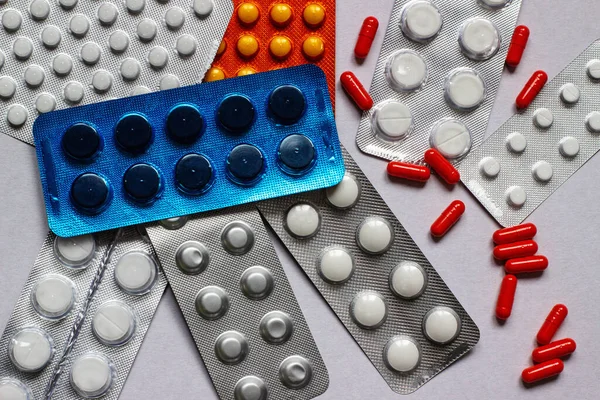 Capsules and tablets are packaged in blisters, isolated on white cardboard. Pharmaceutical industry. Antimicrobial resistance concept, selective focus, medical concept.