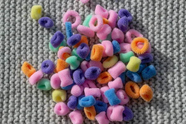 Colorful elastic bands on a gray knitted background used for hair. Multi-colored elastic bands to decorate childrens hairstyles