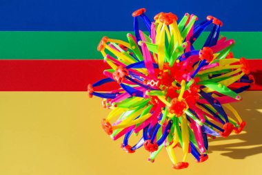 Sarı, mavi, yeşil, kırmızı arka plan ve plastik çubuklardan yapılmış hacimli çok renkli top. Üst manzara, düz yatış. Soyut geometrik şekil, kopyalama alanı, çocuk gelişimi, çocuklar için oyunlar.