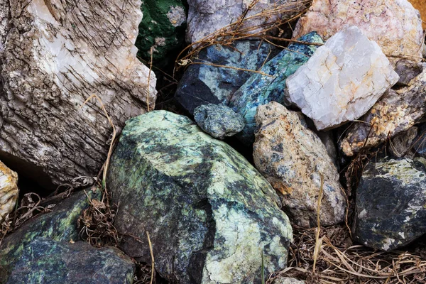 Many beautiful large colored stones are collected in a heap in nature, in the country. Stones close-up, background. Large stones for decorating a summer cottage