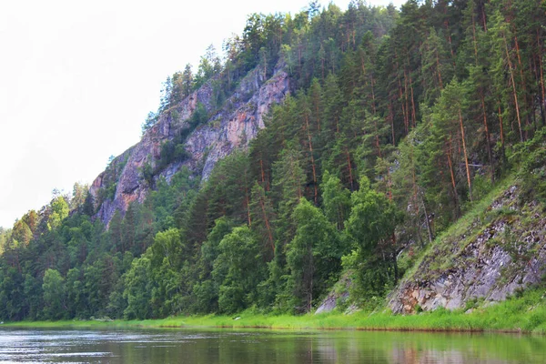 Napsütéses nap a folyón a sziklák és a zöld erdő között. Szabadtéri tevékenységek, utazás a folyó mentén, másolás, lágy fókusz. Gyönyörű táj a tó között hegyek és tűlevelű erdők — Stock Fotó