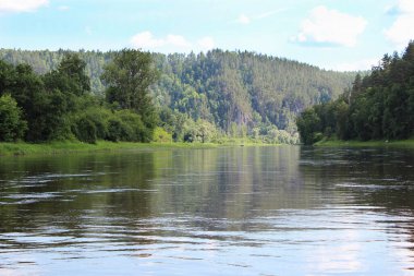 Büyük nehir ve yaz doğası. Dağlardaki bir göl ve ormanın manzarası. Sudaki yansıma, orman nehri ve çamlar.