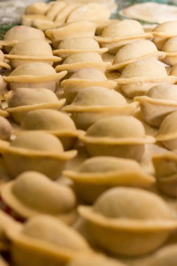 Masada kıymalı ev yapımı hamur tatlısı. Rus ulusal yemeği. Ulusal yemek, çiğ hamur köfteleri yakın plan. Gerçek ev yemeği. Seçici odak.