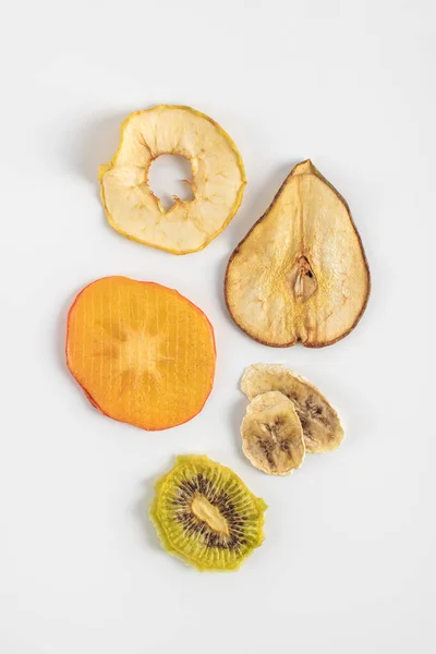 Un bocadillo saludable. chips de frutas deshidratadas caseras sobre un fondo blanco. Kiwi seco, plátano, jabalí, caqui, pera. Nutrición dietética . —  Fotos de Stock
