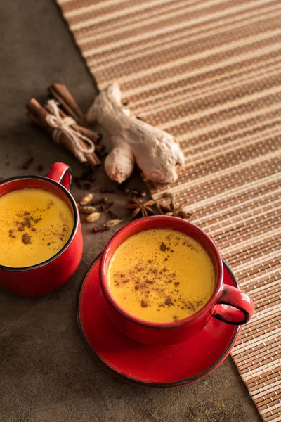 Red cup of golden milk with turmeric powder and cinnamon on a dark background. View from above. A healthy drink to enhance immunity. Healthy drink. Super food — Stock Photo, Image