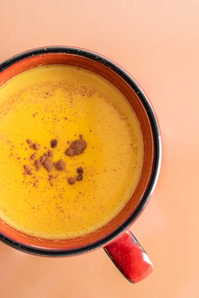 A cup of golden milk with turmeric and cinnamon powder is shot close. View from above. A healthy drink to enhance immunity. Healthy drink. Super food