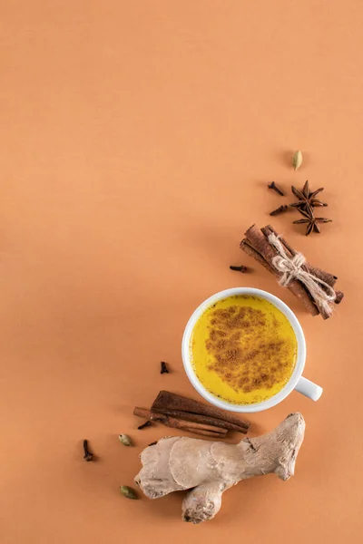 Copa blanca de leche dorada con cúrcuma y canela en polvo sobre un fondo rojo claro con lugar para el texto. Una bebida saludable para mejorar la inmunidad . —  Fotos de Stock