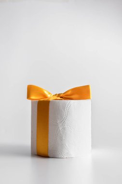 Beyaz arka planda sarı bir kurdeleyle bağlanmış tuvalet kağıdı. Coronavirus. Sadece eğlence için.