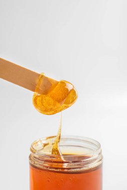 Spatulanın tüy dökümü için sıvı sarı balmumu ya da şeker macunu. Yakın plan. Sağlık ve güzellik kavramı