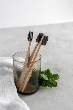 Arka planda bir bardakta üç bambu diş fırçası. Zero West konsepti. Boşluğu kopyala