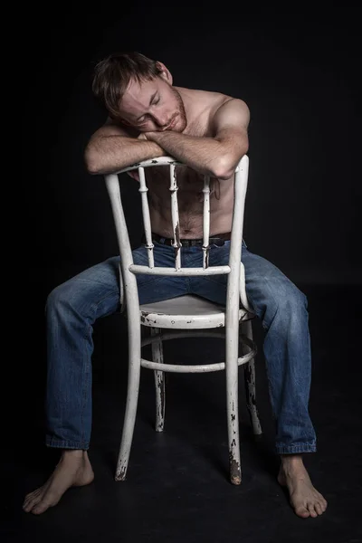 half-naked man tired on a chair in the studio