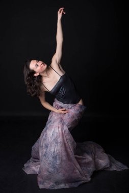 Siyah arka planda uzun eşarplı güneş gözlüklü dansçı