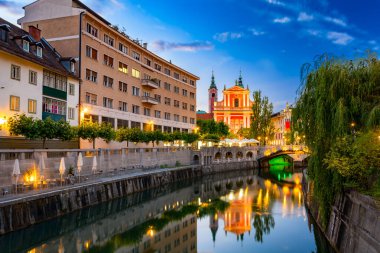 Ljubljanica nehri ve Fransisken kilisesi arka planda bir yaz akşamı Ljubljana 'da