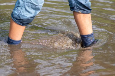 Sel sularının hendeği yarıp geçmesinden sonra ıslak çoraplar ve ıslak botlarla süzülen kısa mavi salyangozlu genç çocuk.