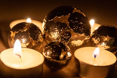 Noel mumlarının romantik mum ışıkları Noel arifesinden önceki gece ve sonraki zaman boyunca pırıl pırıl parlayan metal toplar şeklinde Noel süslemeleri.