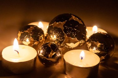 Noel mumlarının romantik mum ışıkları Noel arifesinden önceki gece ve sonraki zaman boyunca pırıl pırıl parlayan metal toplar şeklinde Noel süslemeleri.