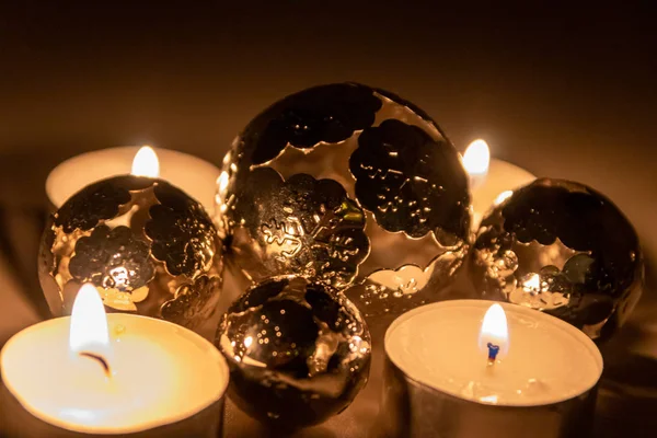 Romantic candle lights of christmas candles with christmas decoration in form of shiny glowing metal balls to shimmer in the night before christmas eve and through the advent time