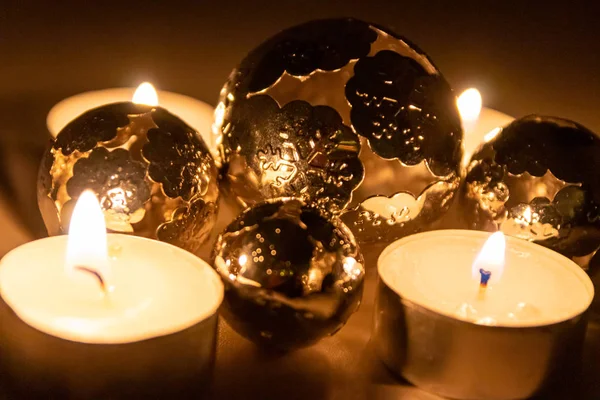 Romantic candle lights of christmas candles with christmas decoration in form of shiny glowing metal balls to shimmer in the night before christmas eve and through the advent time