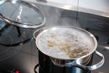 Sıcak buhar ve tencereyle mutfakta yemek pişirmek aile için sağlıklı beslenme, lezzetli öğle yemeği ve akşam yemeği hazırlamak için ceran ocağında lezzetli yemekler pişirmek.