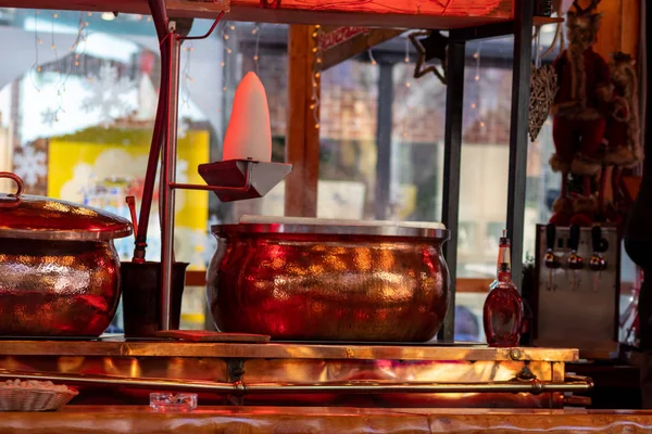 Hot Feuerzangenbowle with sugar loaf and copper kettle steams at a Christmas market and invites visitors to the Christkindlemarkt for a hot drink with red wine, rum and sugar during the Advent season