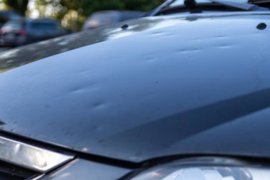 Dolu hasarı olan araba motoru kaputu, doğa gücünü, araba sigortasının önemini ve fırtınalı hava ve fırtına tehlikelerine karşı yeni bir değer sigortası gösteriyor.