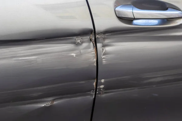 Car damages after a crash with an autonomous car show scratches, bumps and dents, a damaged handgrip and the result of an accident with another car at the backdoor  case for car insurance compensation