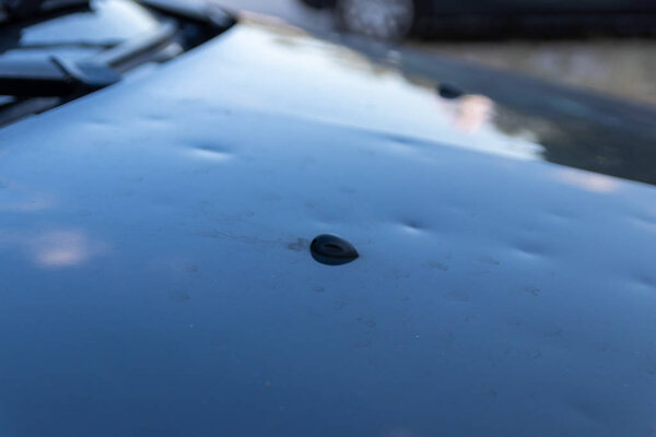 Car engine hood with many hail damage dents show the forces of nature and the importance of car insurance and a replacement value insurance against stormy weather and storm hazards