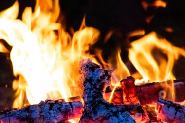 Shiny burning fire in the dark shows the romantic side of a campfire or bonfire, fire safety and the need of a fire insurance as well as survival adventures outdoor with the children and the family
