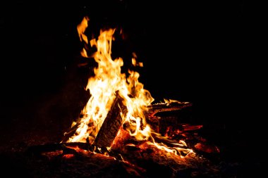 Shiny burning fire in the dark shows the romantic side of a campfire or bonfire, fire safety and the need of a fire insurance as well as survival adventures outdoor with the children and the family