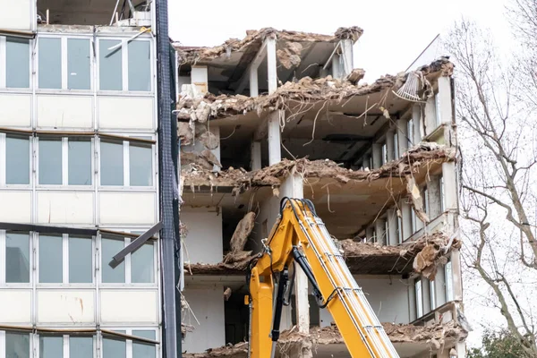 Demolition of a building at a construction yard in the city with heavy machinery like bulldozers and hydraulic excavator as construction equipment do rebuild urban architecture with broken industry