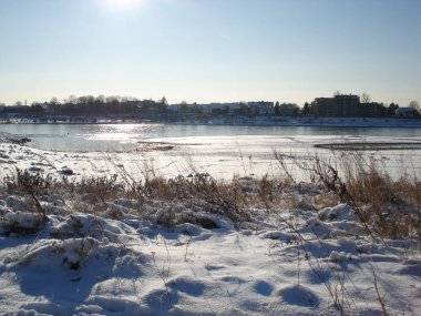 Güneşli kış gününde karlı nehir kıyısında