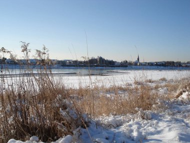 Güneşli kış gününde karlı nehir kıyısında