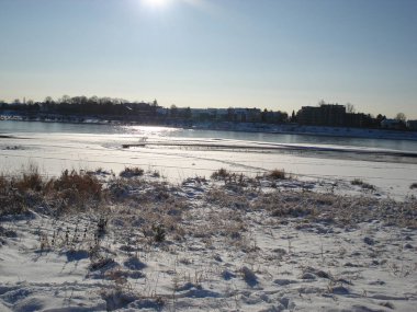 Güneşli kış gününde karlı nehir kıyısında
