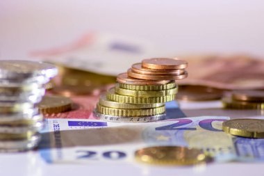 Arka plandaki Avrupa sikkeleri yığını ve banka notları, Avro ve Avrupa, Avrupa ticaret ve mali ticaretinin yanı sıra tasarruf, mali başarı ve kredi yönetimi ile uluslararası finansmanı gösteriyor