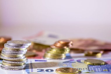 Arka plandaki Avrupa sikkeleri yığını ve banka notları, Avro ve Avrupa, Avrupa ticaret ve mali ticaretinin yanı sıra tasarruf, mali başarı ve kredi yönetimi ile uluslararası finansmanı gösteriyor