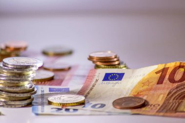 Arka plandaki Avrupa sikkeleri yığını ve banka notları, Avro ve Avrupa, Avrupa ticaret ve mali ticaretinin yanı sıra tasarruf, mali başarı ve kredi yönetimi ile uluslararası finansmanı gösteriyor