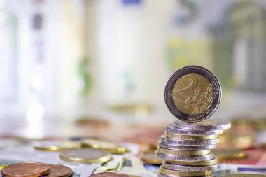 Arka plandaki Avrupa sikkeleri yığını ve banka notları, Avro ve Avrupa, Avrupa ticaret ve mali ticaretinin yanı sıra tasarruf, mali başarı ve kredi yönetimi ile uluslararası finansmanı gösteriyor