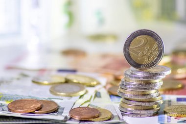 Arka plandaki Avrupa sikkeleri yığını ve banka notları, Avro ve Avrupa, Avrupa ticaret ve mali ticaretinin yanı sıra tasarruf, mali başarı ve kredi yönetimi ile uluslararası finansmanı gösteriyor